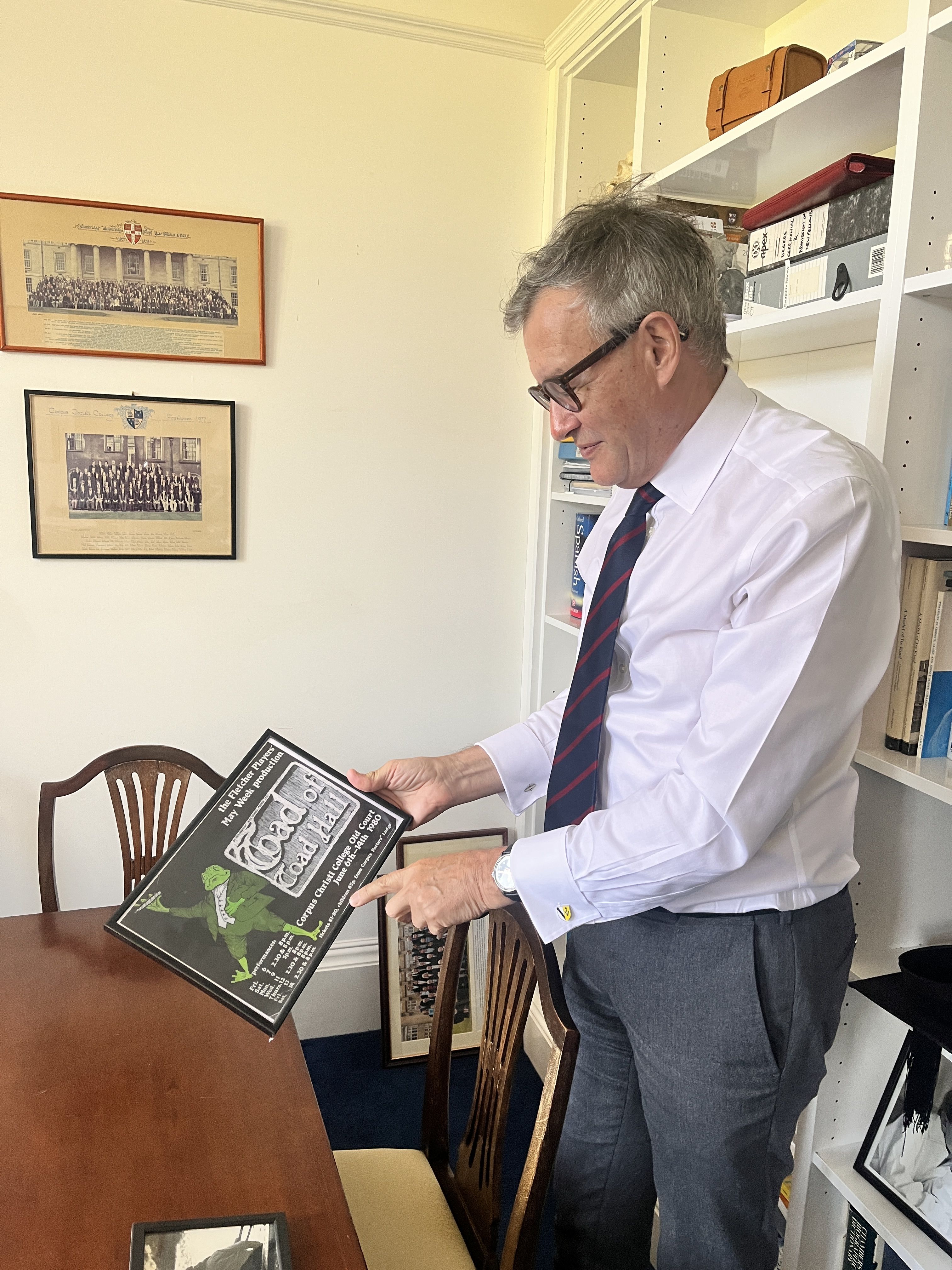 Martin in his office at Sidney Sussex College holding a programme from a production of Toad of Toad Hall from his time at Corpus.